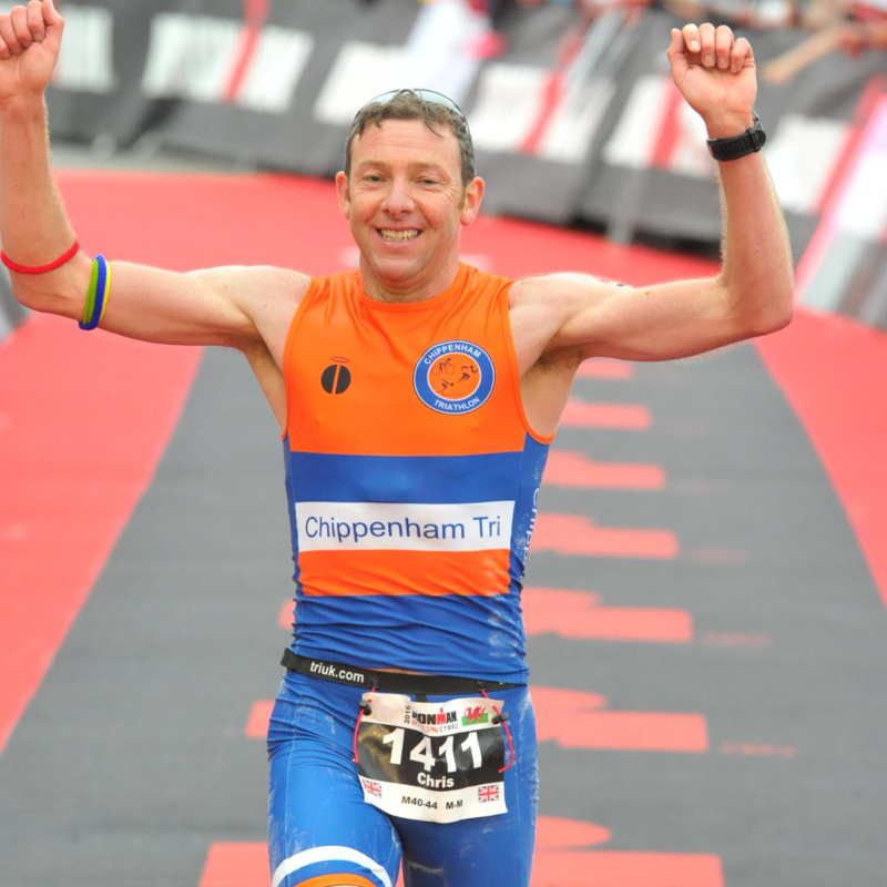 A triathlete crossing the finishing line with his arms in the air